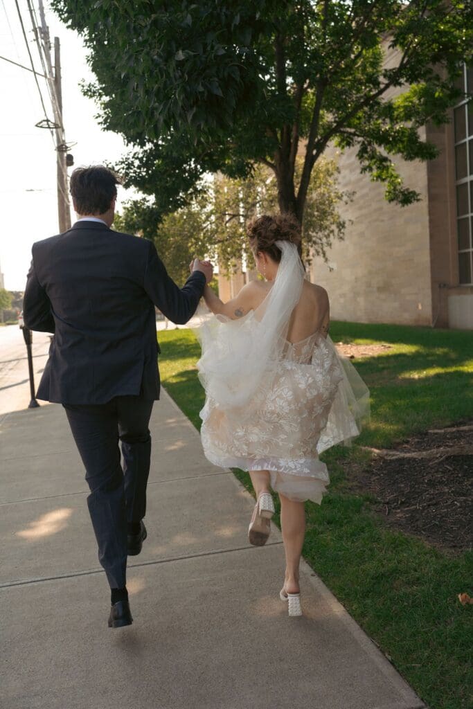 Bridal photos of a Bride and groom skipping down a sunny street