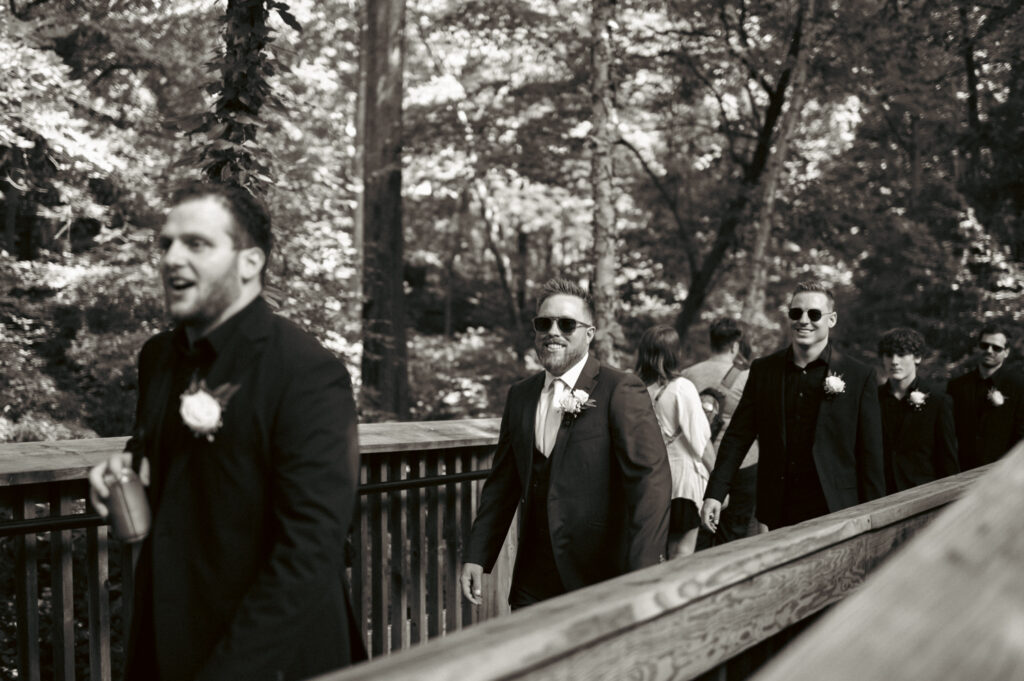 Groomsmen walking across a bridge with sunglasses