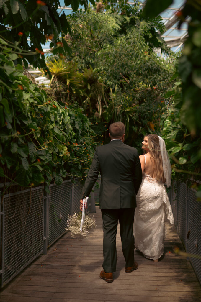 Bride and groom walking through a garden inside the cleveland botanical gardens