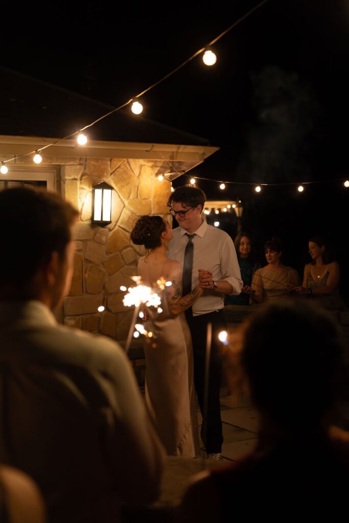 Bride and groom dancing their last dance while guests hold sparklers
