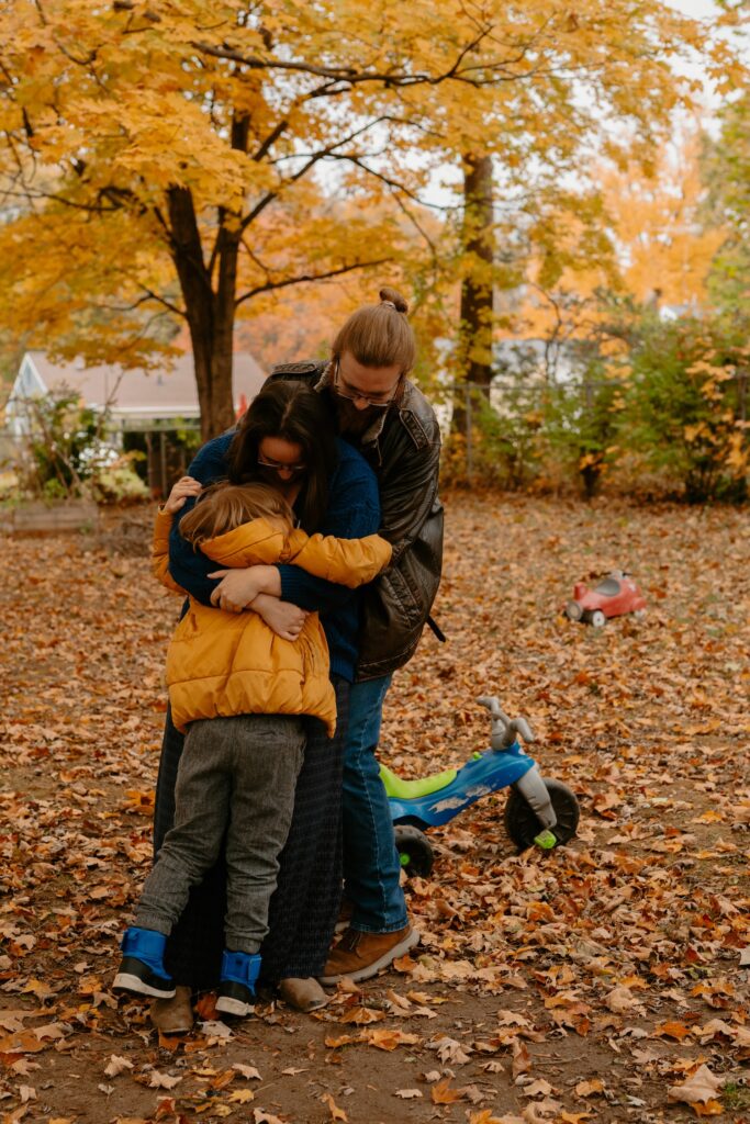 A young boy hugging his mom and dad tightly on a chilly autumn day