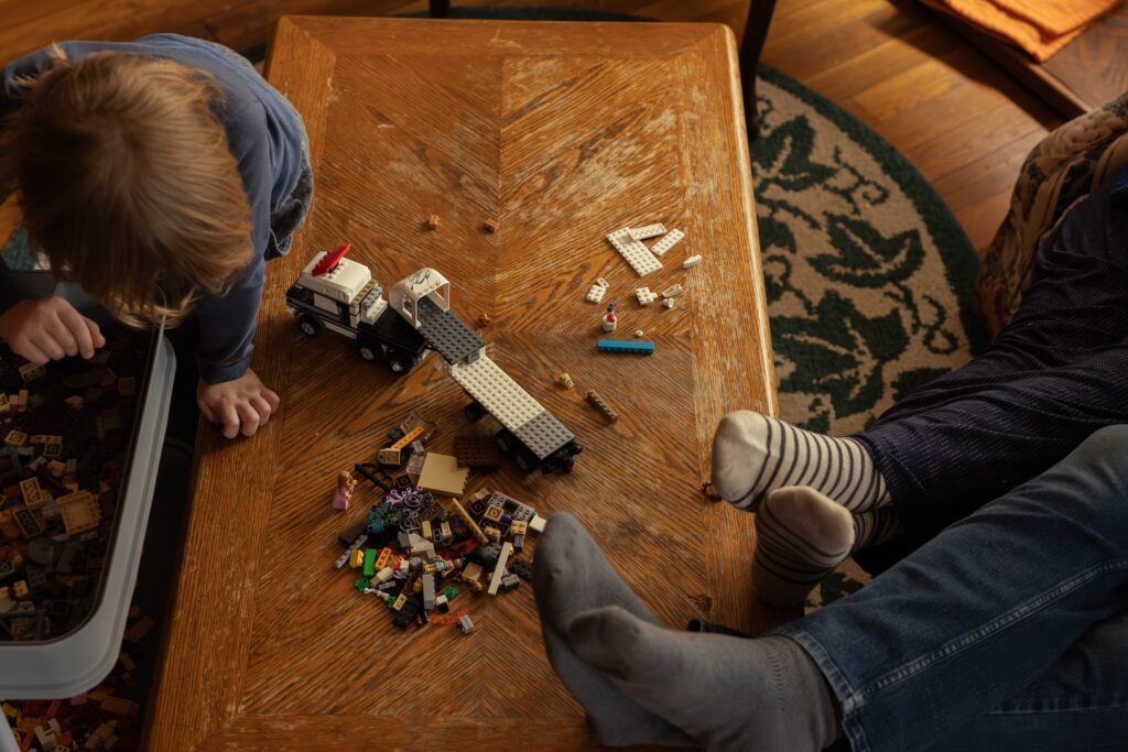 candid photo of a young boy playing with legos while his parents sit on the couch