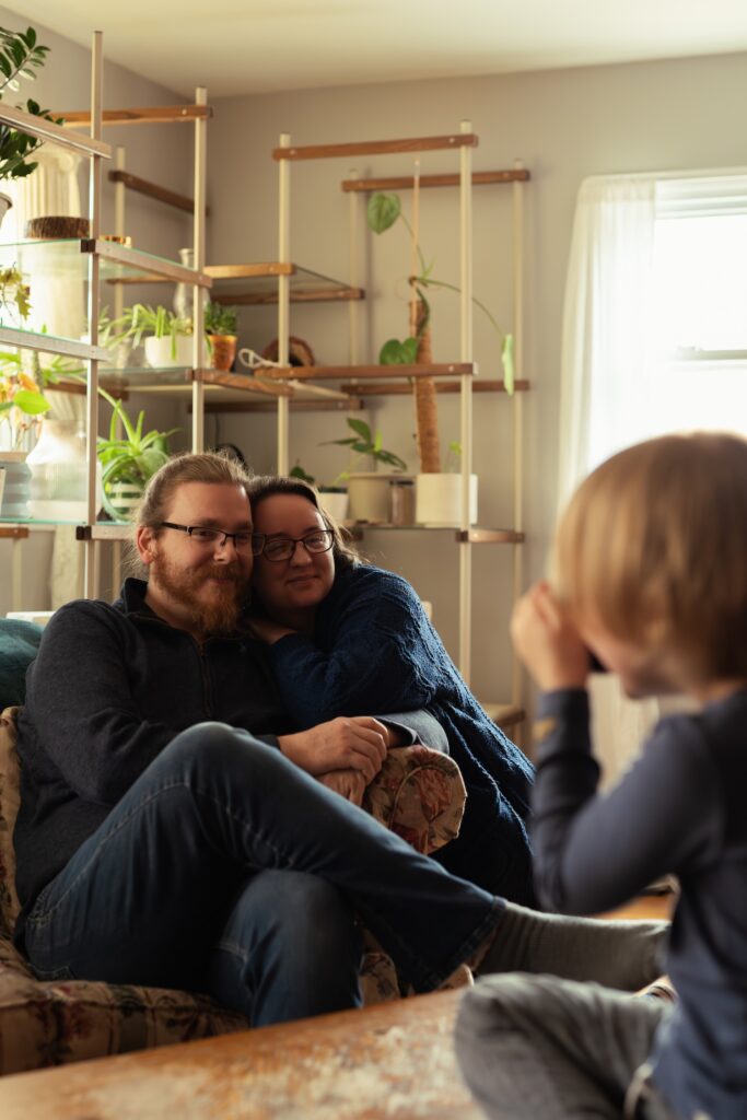 photo of a young boy taking pictures of his mom and dad at home